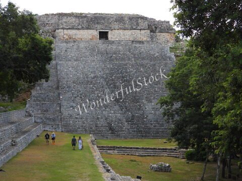 Pyramide à Uxmal, Mexique, avec des visiteurs marchant sur l'herbe et des arbres en arrière-plan.
