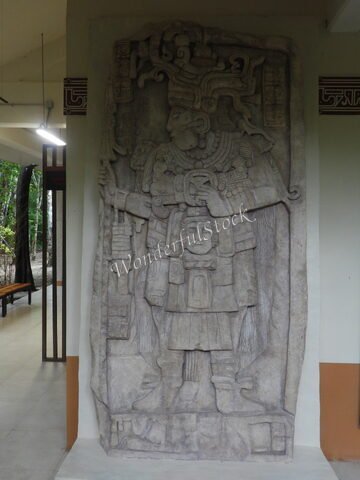 Bas-relief représentant des figures mayas à Calakmul, Mexique, avec des détails sculptés sur la pierre et un cadre architectural moderne.