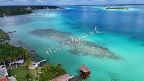 Vue aérienne de Bacalar, Mexique, avec des eaux turquoise et des formations coralliennes visibles.