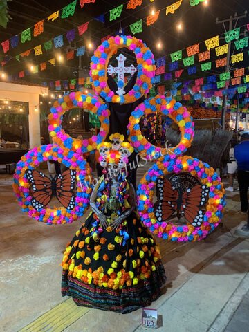 Squelette décoré avec des fleurs colorées et un costume traditionnel, à Cancun, Mexique, entouré de décorations festives.