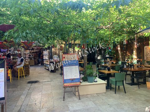 Restaurant en plein air avec des tables et des chaises, sous des arbres, à Ardèche, France.