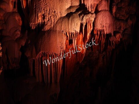 Des stalactites dans la grotte Aven Armand, France, éclairées par une lumière rouge.