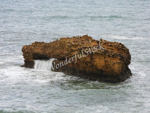 Roche émergeant de l'eau avec une cascade à Biarritz, France.
