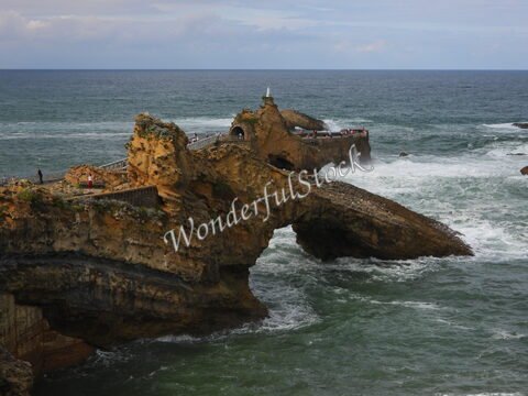 Rocher surplombant la mer à Biarritz, France, avec des vagues et des promeneurs sur la passerelle.