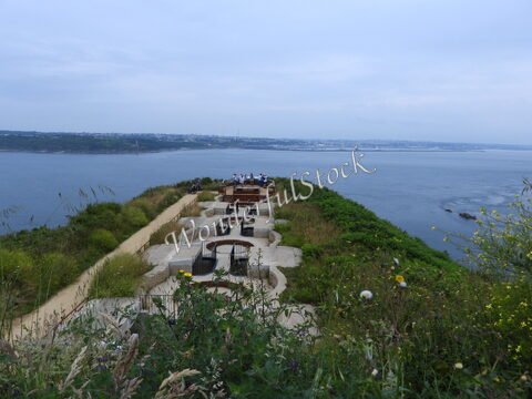 Terrasse surplombant la mer à Crozon, Bretagne, France, avec des sièges en bois et une végétation environnante.