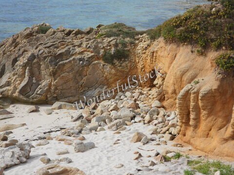 Rochers et galets sur une plage de sable à Bretagne, France, avec une mer calme en arrière-plan.