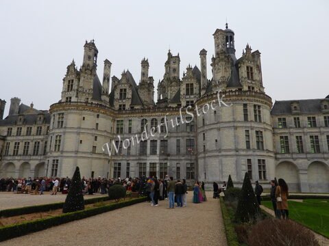 Château de Chambord, France, avec des visiteurs et des arbres taillés en haie dans le jardin.