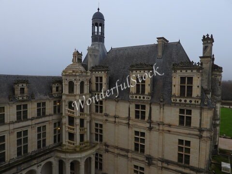 Château à Chambord, France, avec une façade ornée et une tour distinctive, sous un ciel brumeux.