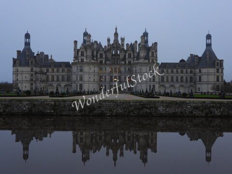 Château de Chambord, France, avec des arbres décorés et un reflet dans l'eau.