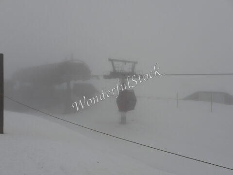 Téléphérique dans le brouillard à Chamrousse, France, avec des pistes de neige visibles et des structures de ski en arrière-plan.