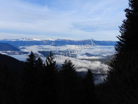 Vue sur des montagnes avec des sommets enneigés et des nuages au-dessus de la vallée à Chamrousse, France.