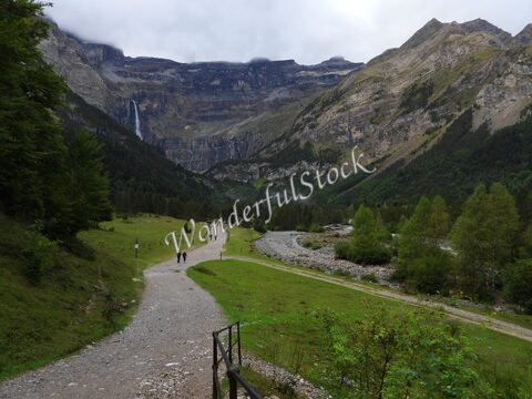 Cirque de Gavarnie, France, avec des montagnes majestueuses et une cascade visible en arrière-plan, le tout entouré de verdure.