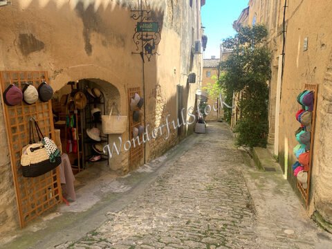 Ruelle de Gordes en France, avec des chapeaux accrochés et des boutiques en pierre.