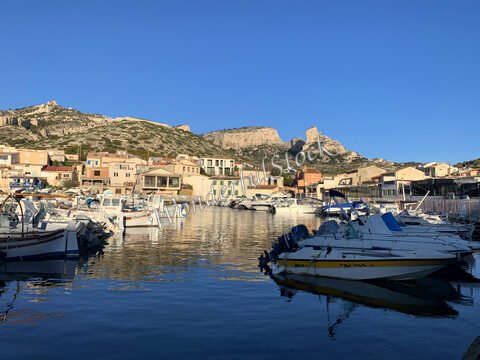 Bateaux amarrés dans un port, avec des maisons colorées et des collines à Marseille, France.