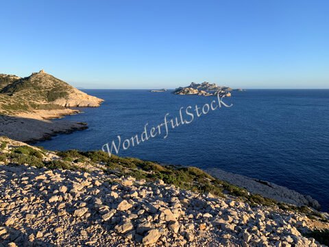 Vue sur la mer à Marseille, France, avec des rochers et des îles au loin sous un ciel dégagé.