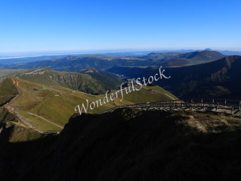 Vue panoramique sur le paysage verdoyant de Mont-Dore, en France, avec des collines et un bâtiment visible au loin.