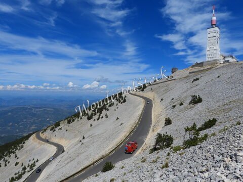 Mont Ventoux en France, avec une route sinueuse et un bâtiment en hauteur, entouré de paysages rocheux et d'un ciel bleu.