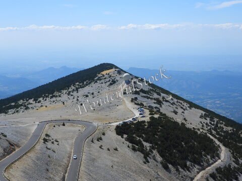 Mont Ventoux en France, avec des routes sinueuses et une station météorologique au sommet, entouré de paysages rocheux et boisés.