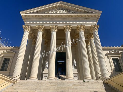 Entrée d'un bâtiment avec de grandes colonnes, à Montpellier, France, avec des statues de chaque côté des marches.