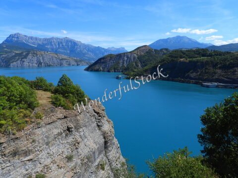 Lac de Serre-Ponçon en France, avec des montagnes en arrière-plan et une eau turquoise.