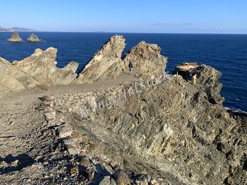 Rochers escarpés surplombant la mer à Six-Fours, France, avec un bâtiment en ruine et des îlots en arrière-plan.