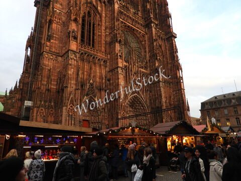 Cathédrale de Strasbourg en France, avec des étals de marché et des visiteurs autour, mettant en avant l'architecture gothique distincte.