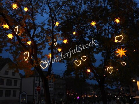 Étoiles et cœurs lumineux décorent des arbres à Strasbourg, France, sous un ciel nocturne.