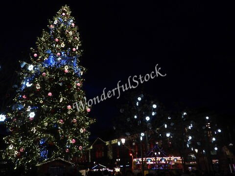Un grand sapin de Noël décoré à Strasbourg, France, entouré de lumières scintillantes et de stands de marché festif.