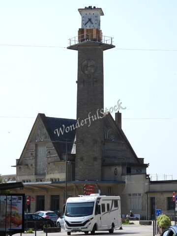 Un bâtiment avec une horloge en hauteur et un camping-car devant, à Dinan, France.