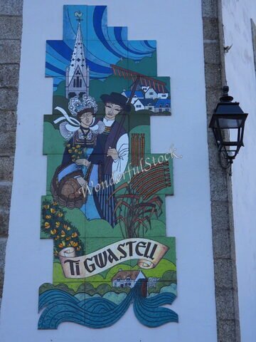 Une fresque colorée représentant des personnages traditionnels au Pont-Aven, France, avec une église et des maisons en arrière-plan.