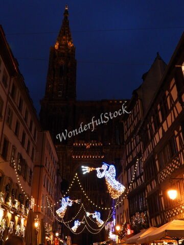 Illuminations festives décorent une rue à Strasbourg, France, avec en arrière-plan la cathédrale illuminée.
