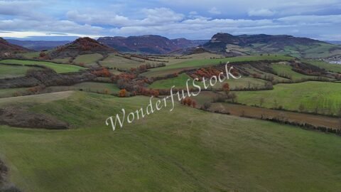 Vaste paysage vallonné à Roquefort, France, avec des champs verdoyants et des arbres aux teintes automnales.